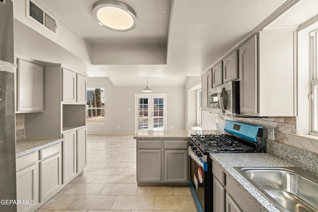 kitchen featuring visible vents, a peninsula, a sink, gray cabinetry, and stainless steel appliances