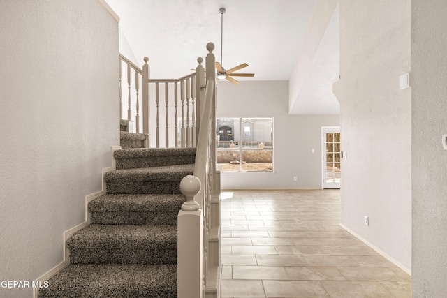 staircase featuring baseboards and ceiling fan