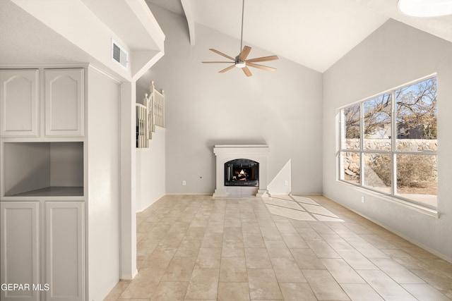 unfurnished living room with lofted ceiling, visible vents, a warm lit fireplace, and ceiling fan