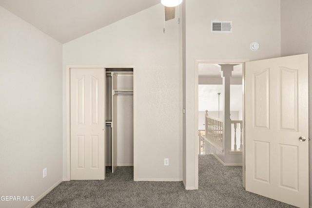 unfurnished bedroom featuring visible vents, a closet, dark carpet, and vaulted ceiling