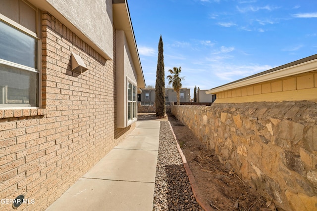 view of side of home with brick siding and fence