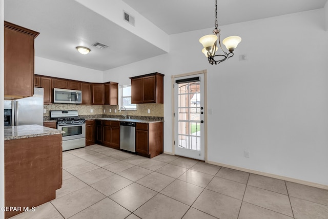 kitchen featuring light stone countertops, visible vents, an inviting chandelier, appliances with stainless steel finishes, and backsplash