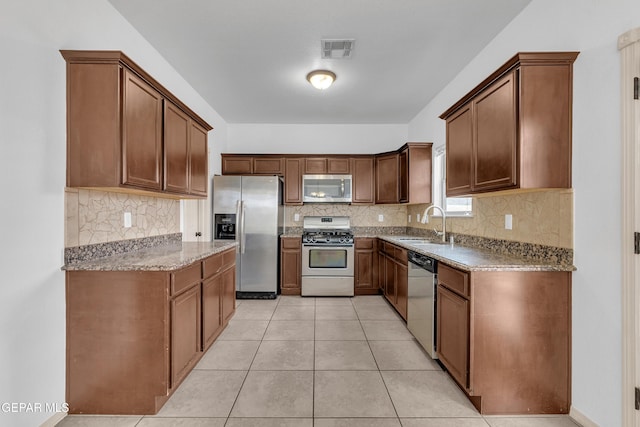 kitchen with visible vents, a sink, stainless steel appliances, light tile patterned floors, and light stone countertops