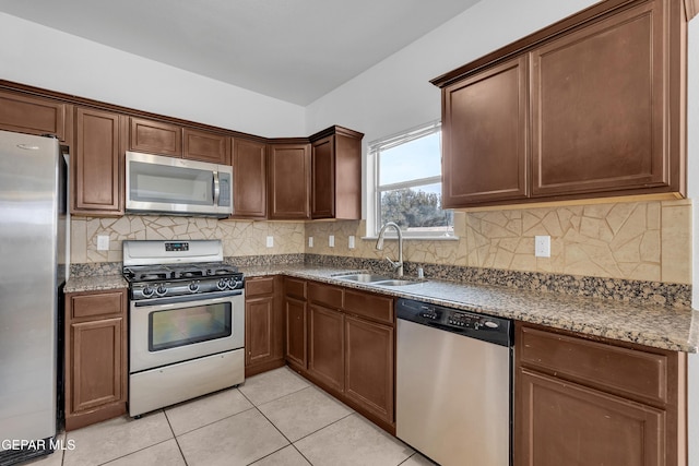 kitchen featuring a sink, stainless steel appliances, backsplash, and light tile patterned floors