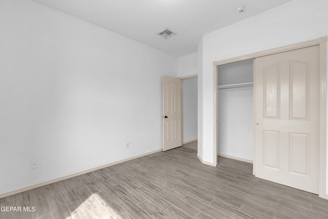 unfurnished bedroom featuring a closet, visible vents, baseboards, and light wood-style floors