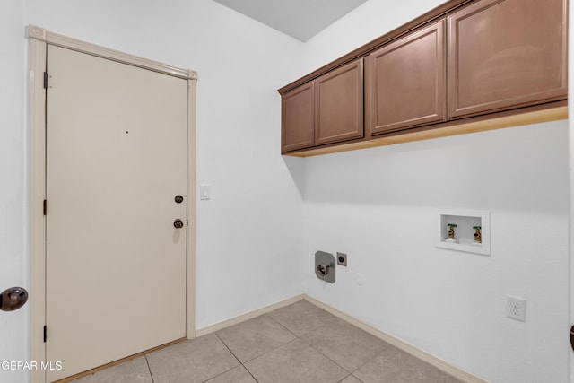 laundry area with electric dryer hookup, washer hookup, cabinet space, light tile patterned floors, and baseboards