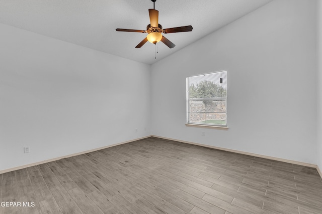 spare room with baseboards, wood finished floors, a ceiling fan, and vaulted ceiling