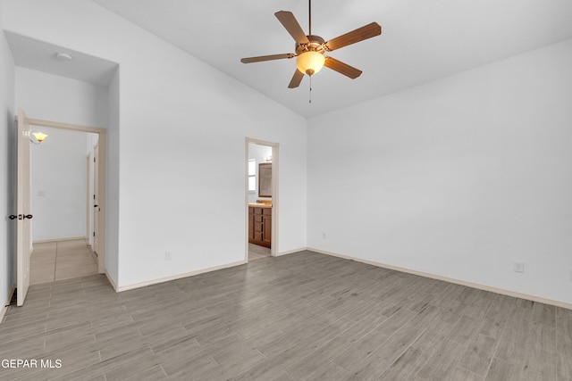 unfurnished bedroom with light wood finished floors, baseboards, ensuite bathroom, and lofted ceiling