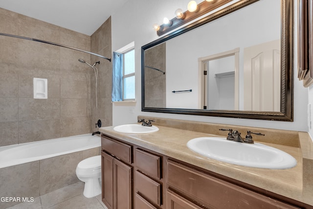 bathroom featuring a sink, tiled shower / bath, toilet, and tile patterned flooring