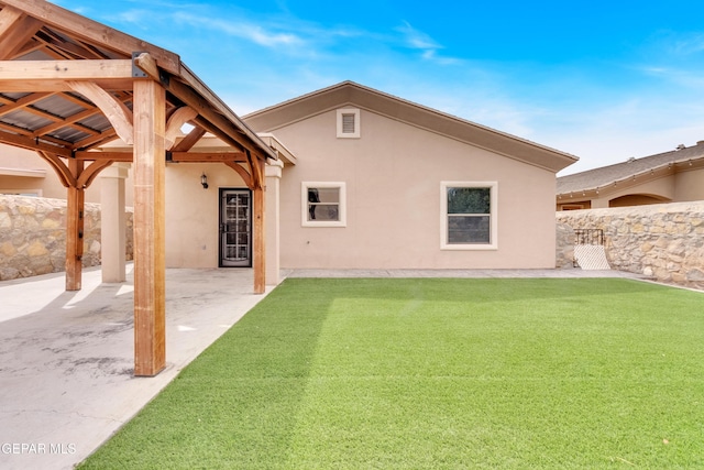 rear view of house with stucco siding, a patio, a lawn, and fence