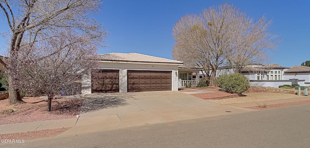 view of front of house featuring fence, a tile roof, concrete driveway, stucco siding, and an attached garage