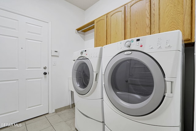 washroom featuring cabinet space, light tile patterned floors, and washing machine and dryer