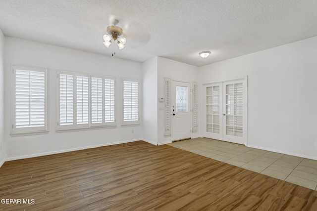 foyer featuring a textured ceiling, wood finished floors, baseboards, and ceiling fan