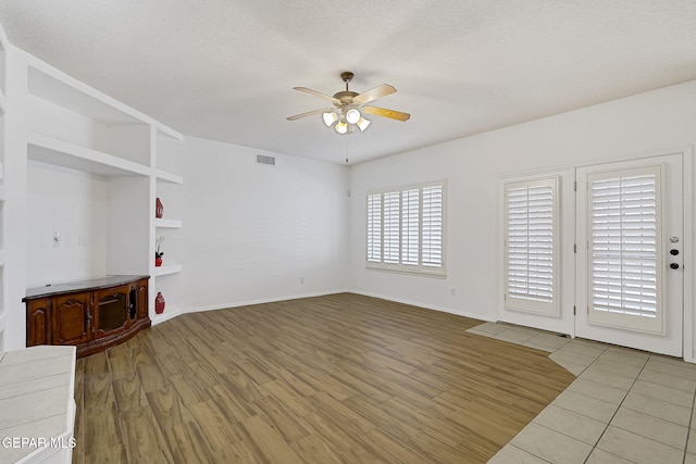 unfurnished living room featuring visible vents, wood finished floors, baseboards, and ceiling fan