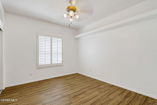 unfurnished room featuring a textured ceiling, baseboards, and wood finished floors