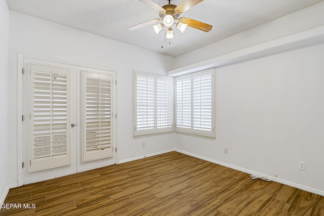 unfurnished bedroom featuring ceiling fan, a textured ceiling, baseboards, and wood finished floors