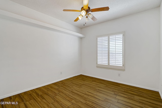 empty room with a textured ceiling, baseboards, and wood finished floors