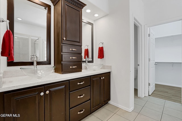 full bathroom featuring a sink, baseboards, double vanity, and tile patterned floors