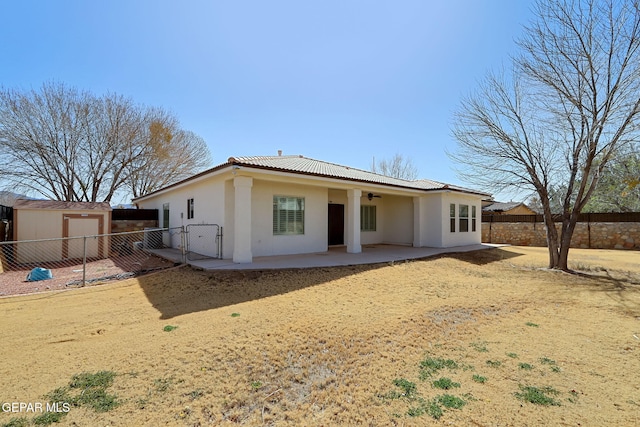 rear view of property with ceiling fan, fence, a tile roof, stucco siding, and a patio