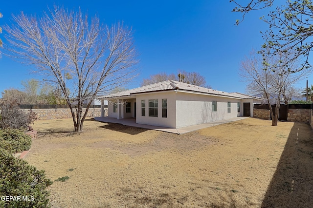 rear view of house with stucco siding, a patio, a fenced backyard, and a tiled roof