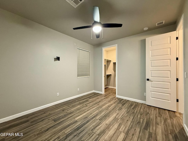 unfurnished bedroom with baseboards, visible vents, dark wood finished floors, a spacious closet, and a closet