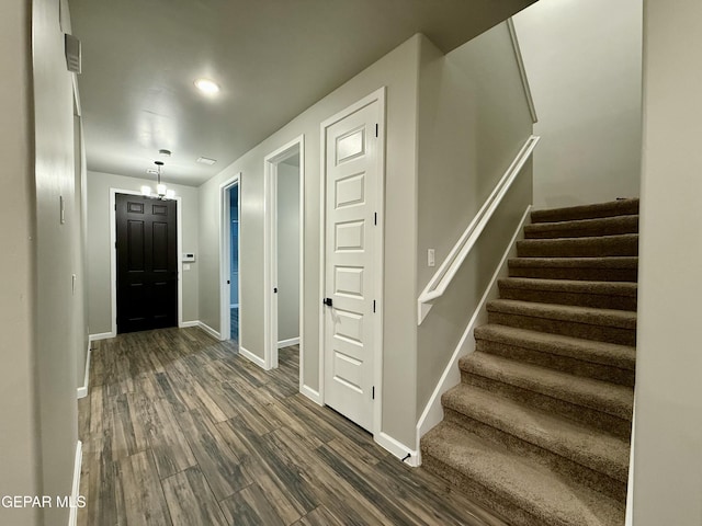 entrance foyer featuring stairs, baseboards, an inviting chandelier, and dark wood-style flooring