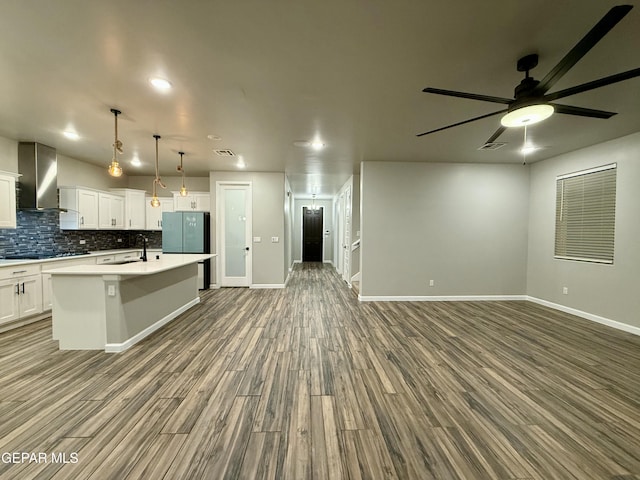 kitchen featuring decorative backsplash, wall chimney range hood, open floor plan, and a sink