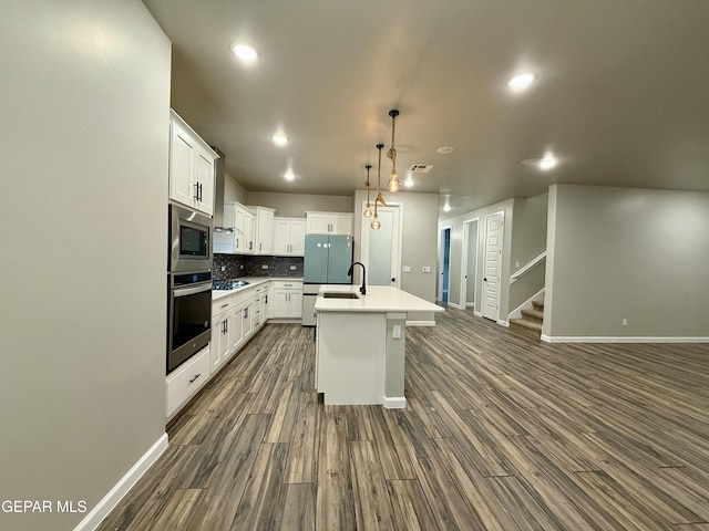 kitchen with an island with sink, dark wood-style floors, white cabinetry, appliances with stainless steel finishes, and decorative backsplash