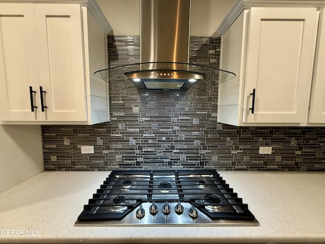 details featuring stainless steel gas cooktop, range hood, white cabinetry, and backsplash