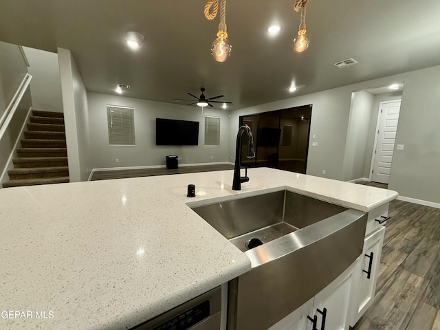 kitchen featuring visible vents, light stone countertops, wood finished floors, white cabinetry, and a ceiling fan