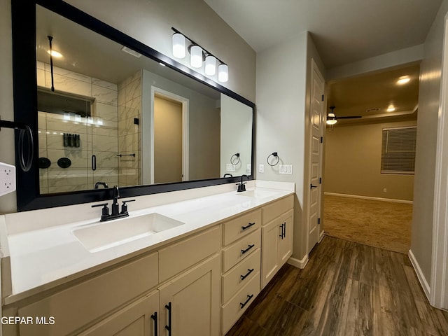 full bath with double vanity, wood finished floors, a stall shower, and a sink