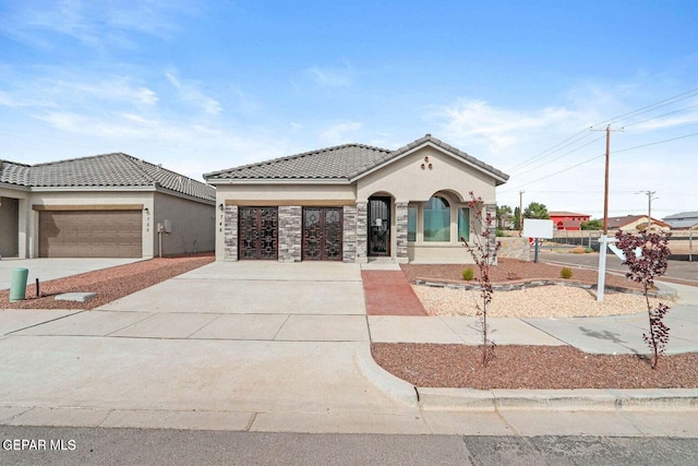 mediterranean / spanish-style home featuring a tiled roof, stucco siding, an attached garage, and driveway