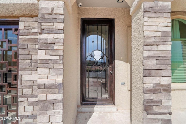 property entrance featuring stone siding and stucco siding