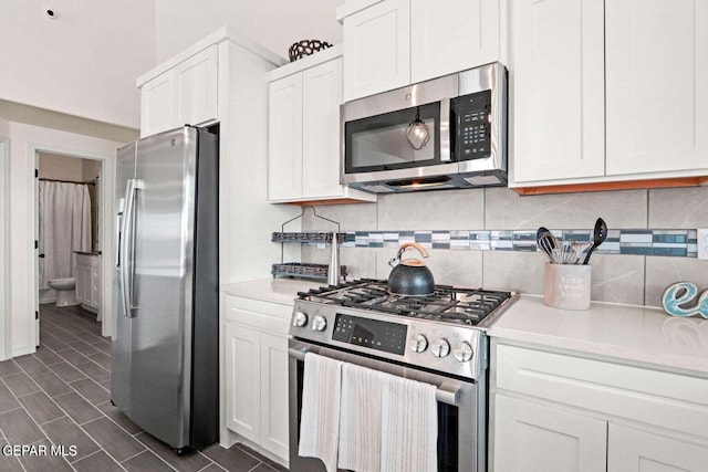 kitchen featuring stainless steel appliances, white cabinetry, backsplash, and light countertops