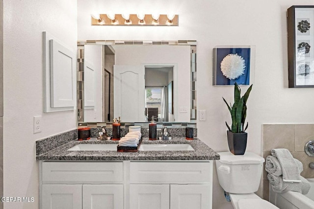 bathroom featuring double vanity, toilet, and a sink