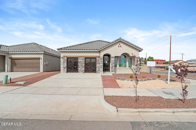 mediterranean / spanish home featuring concrete driveway, a tiled roof, an attached garage, and stucco siding