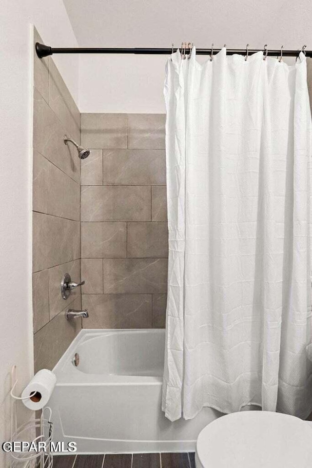 bathroom with shower / tub combo, toilet, and wood finished floors