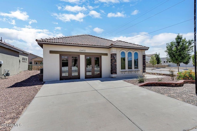 rear view of property with a tile roof, french doors, and stucco siding