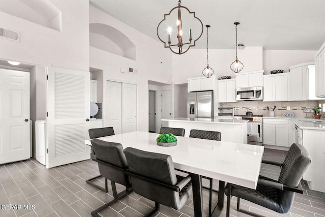 dining space featuring a chandelier, visible vents, and high vaulted ceiling