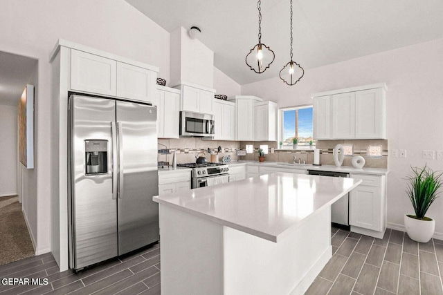 kitchen with tasteful backsplash, white cabinetry, stainless steel appliances, and vaulted ceiling