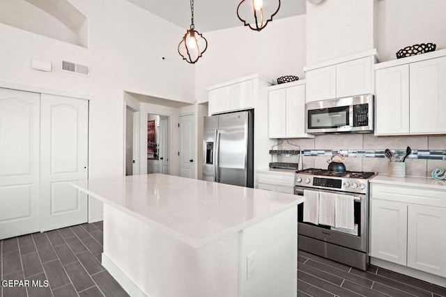 kitchen with visible vents, backsplash, wood finish floors, stainless steel appliances, and white cabinetry