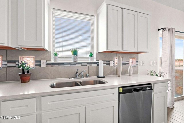 kitchen with a sink, decorative backsplash, dishwasher, and white cabinets