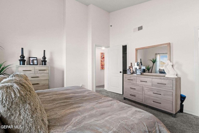 carpeted bedroom featuring visible vents and a towering ceiling