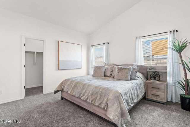 carpeted bedroom featuring a walk in closet, vaulted ceiling, and baseboards