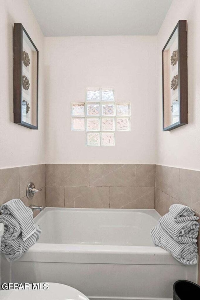 full bathroom featuring a garden tub and toilet