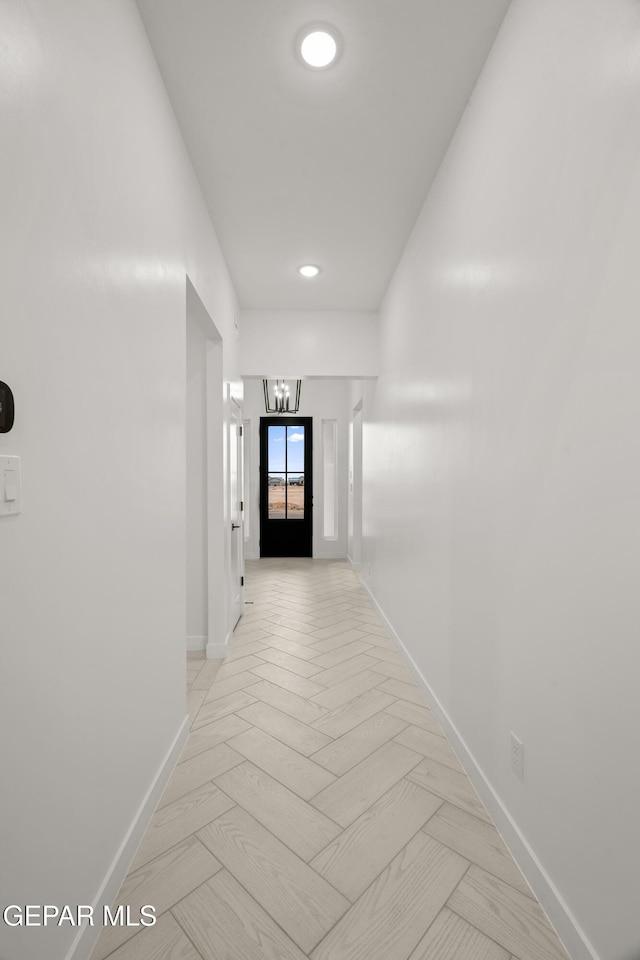 hall with a notable chandelier and baseboards