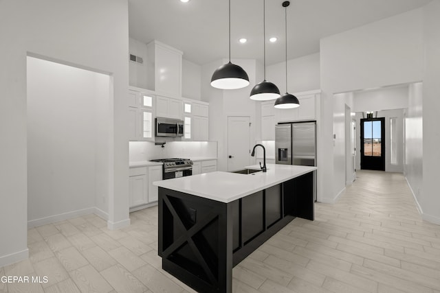 kitchen with a towering ceiling, visible vents, appliances with stainless steel finishes, and a sink