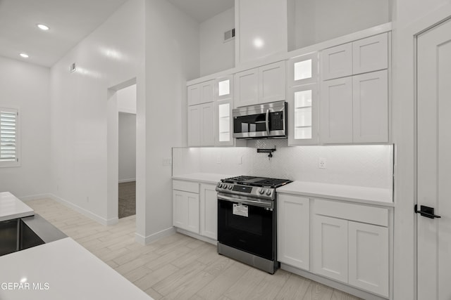 kitchen with white cabinetry, backsplash, visible vents, and appliances with stainless steel finishes