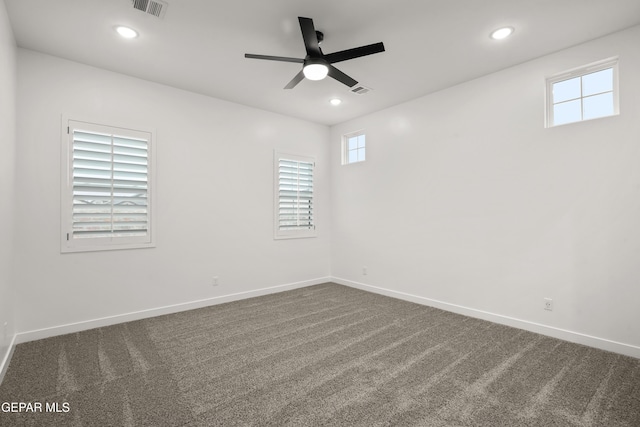 unfurnished room featuring dark colored carpet, visible vents, baseboards, and a ceiling fan