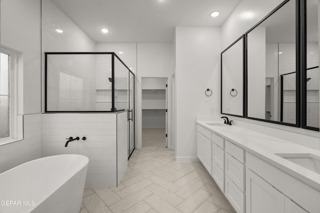 bathroom featuring double vanity, a freestanding tub, a stall shower, and a sink